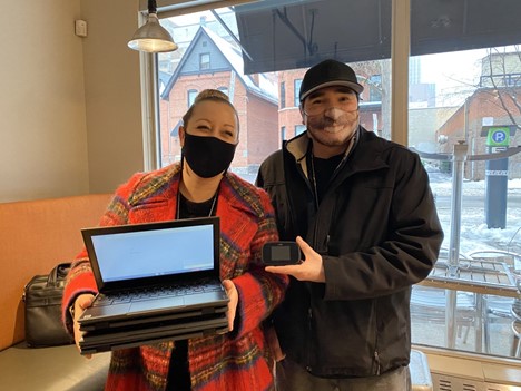 Jennifer Valiquette (Court Worker) and Greg Meekis (Bail Supervisor) from Odawa Native Friendship Centre holding up Chromebooks and a wifi hotspot borrowed from OPL for their clients